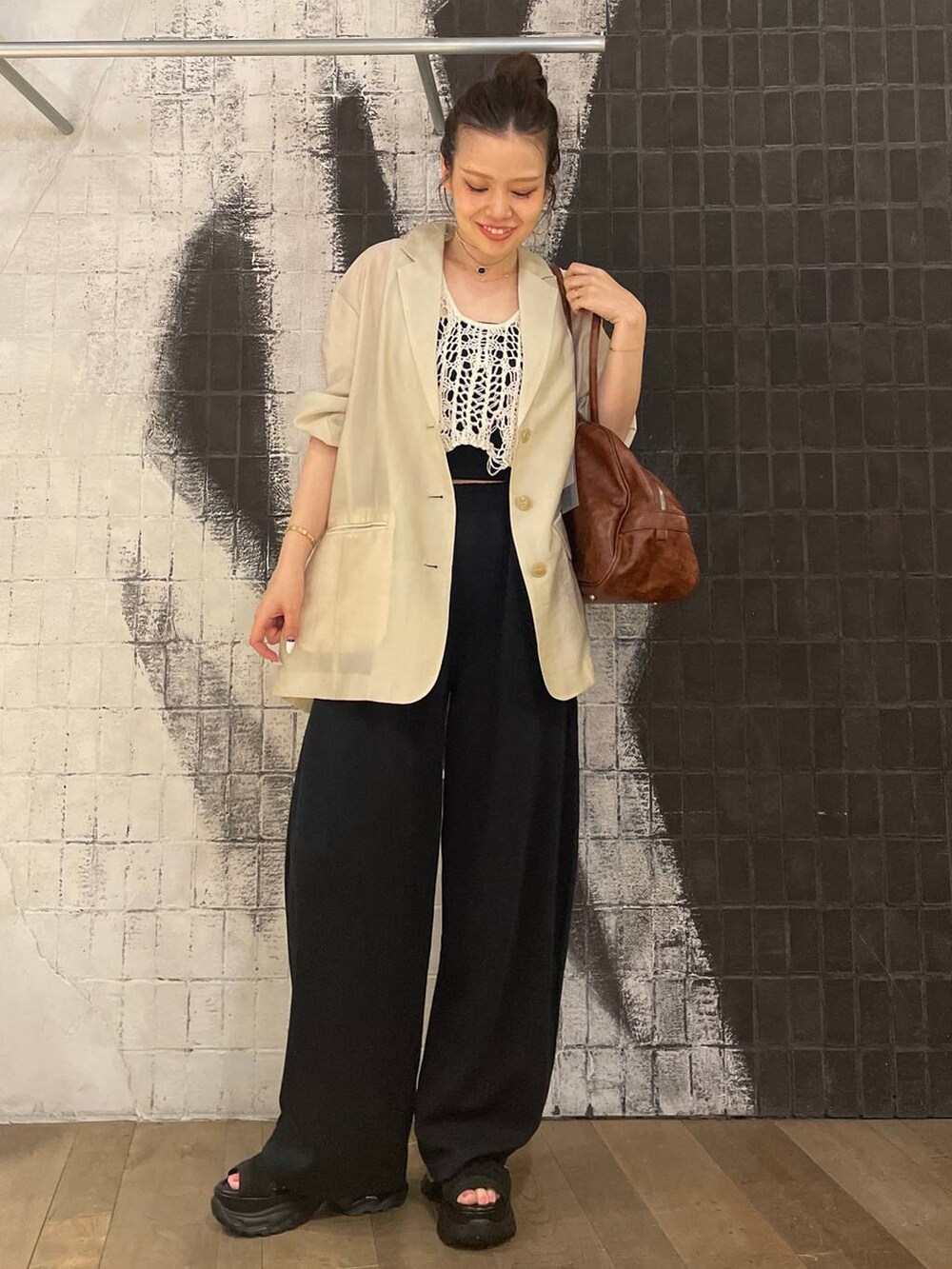 ホワイト系のベスト、ブラック系のサンダル、ブラウン系のボストンバッグを着用したレディースの夏コーディネートの4枚目の写真