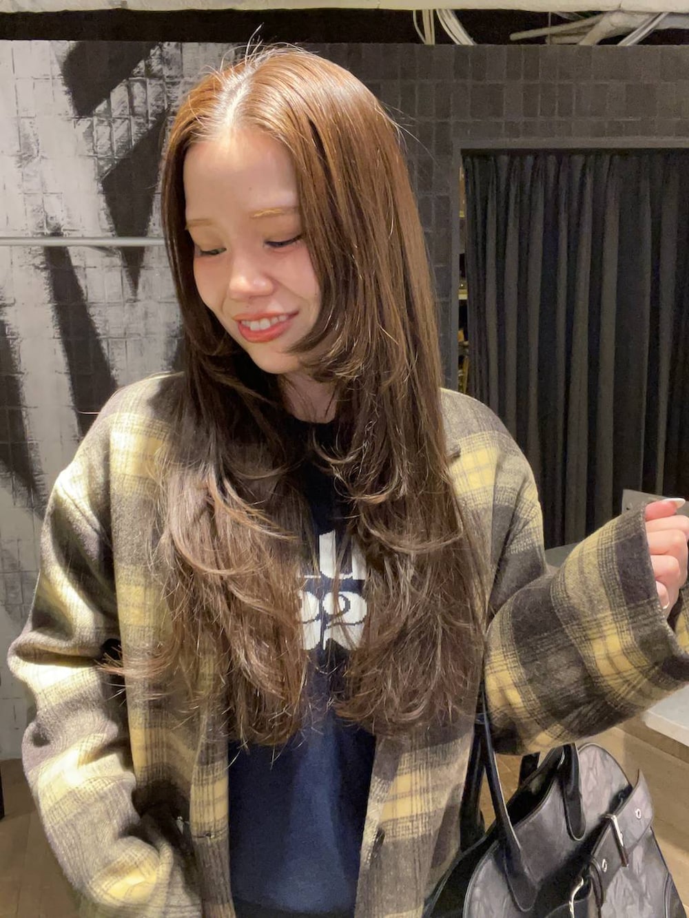 グレー系のブーツ、ブラウン系のチェスターコート、ブラック系のショルダーバッグを着用したレディースの冬コーディネートの4枚目の写真