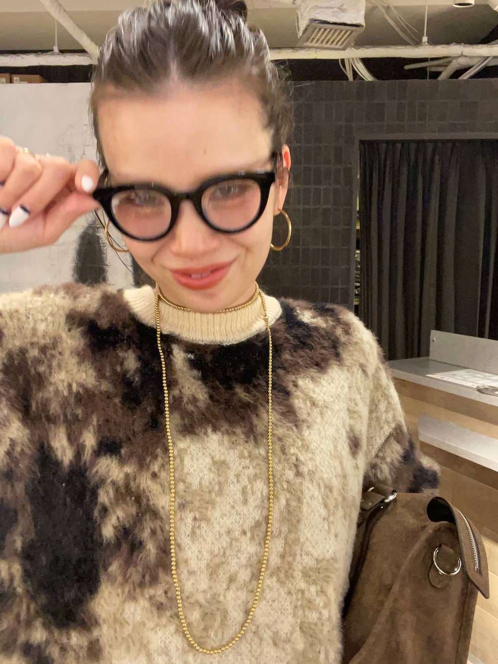 ブラウン系のニット/セーター、ブルー系のデニムパンツ、ブラウン系のボストンバッグを着用したレディースの冬コーディネートの5枚目の写真