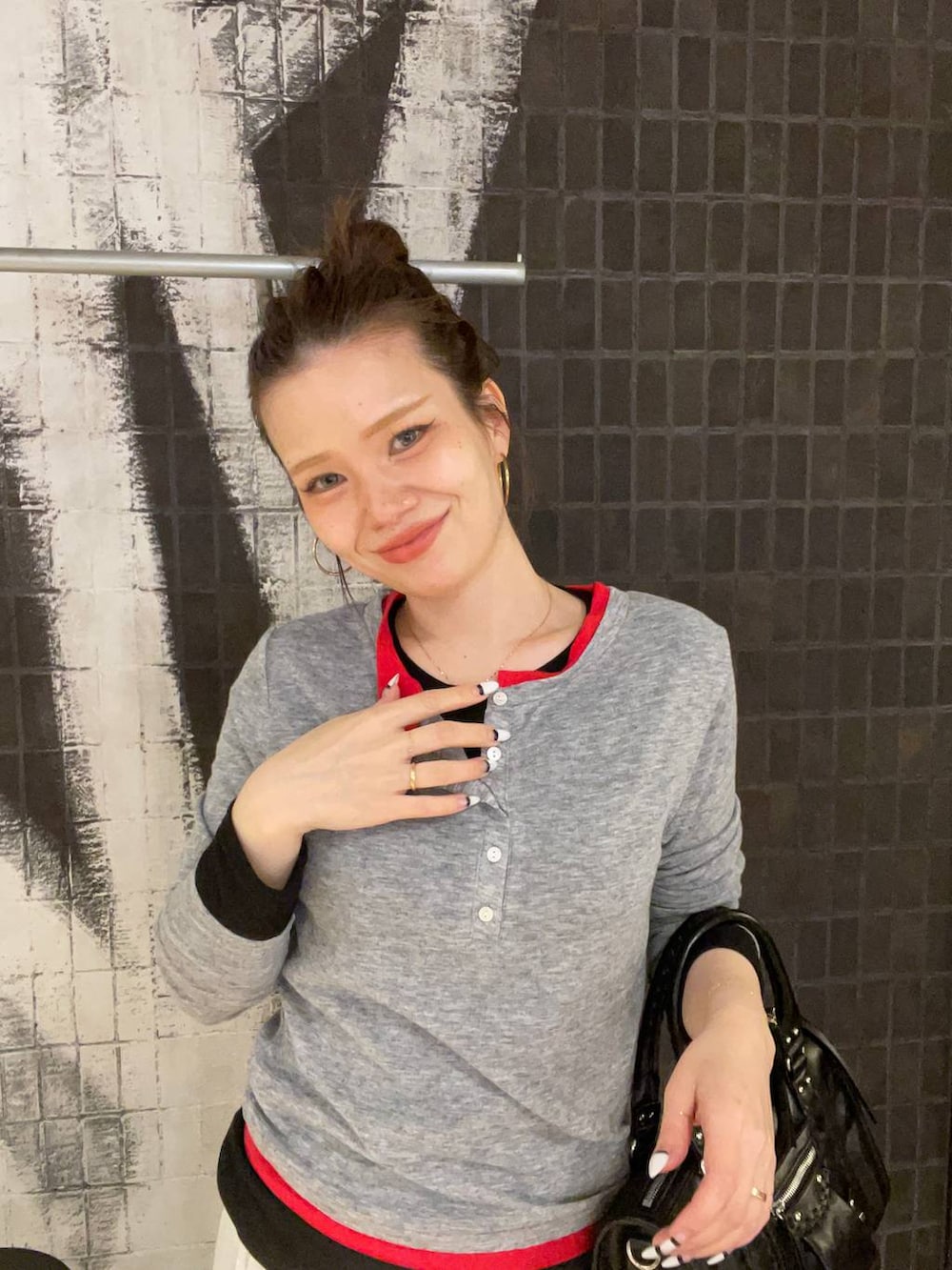 ブラック系のスニーカー、ブラック系のボストンバッグ、グレー系のスカートを着用したレディースの春コーディネートの5枚目の写真