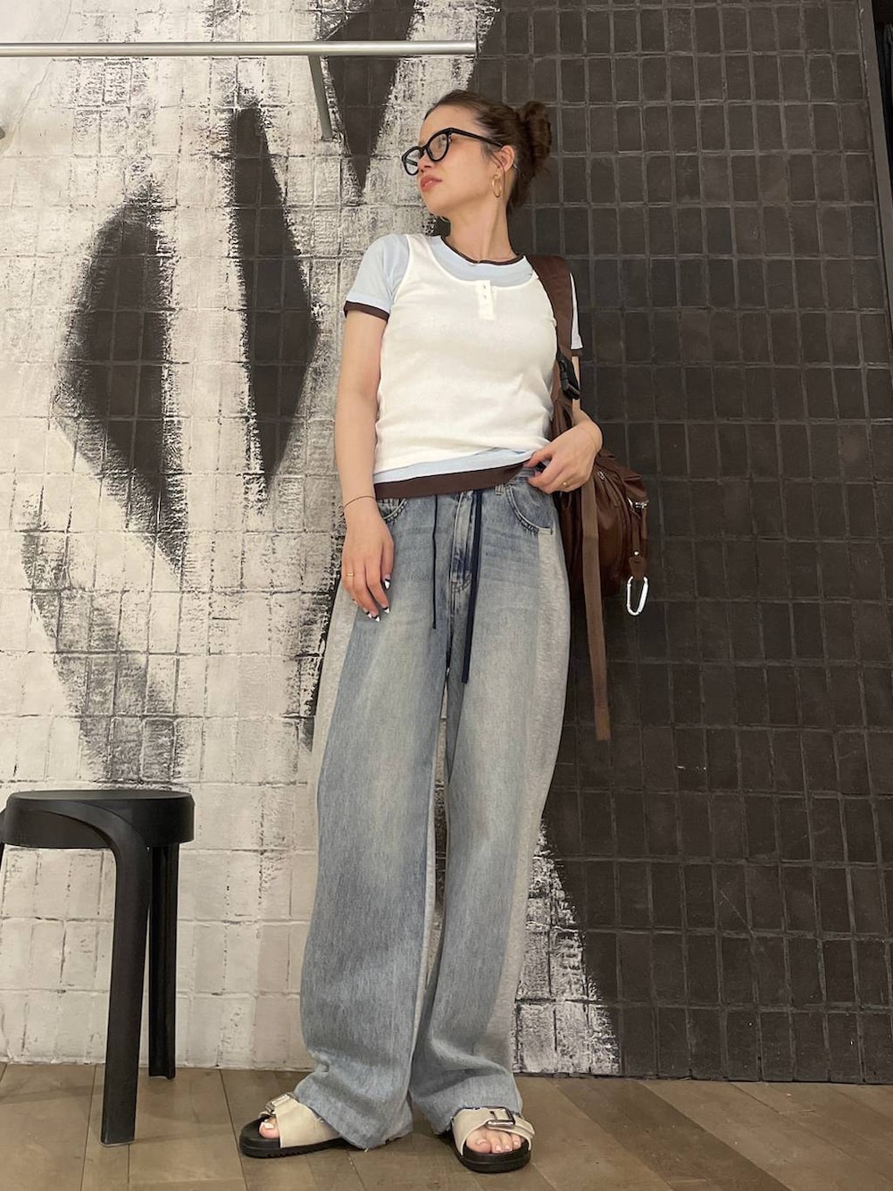 ブラウン系のショルダーバッグ、ブルー系のデニムパンツ、ホワイト系のタンクトップを着用したレディースの春コーディネートの4枚目の写真