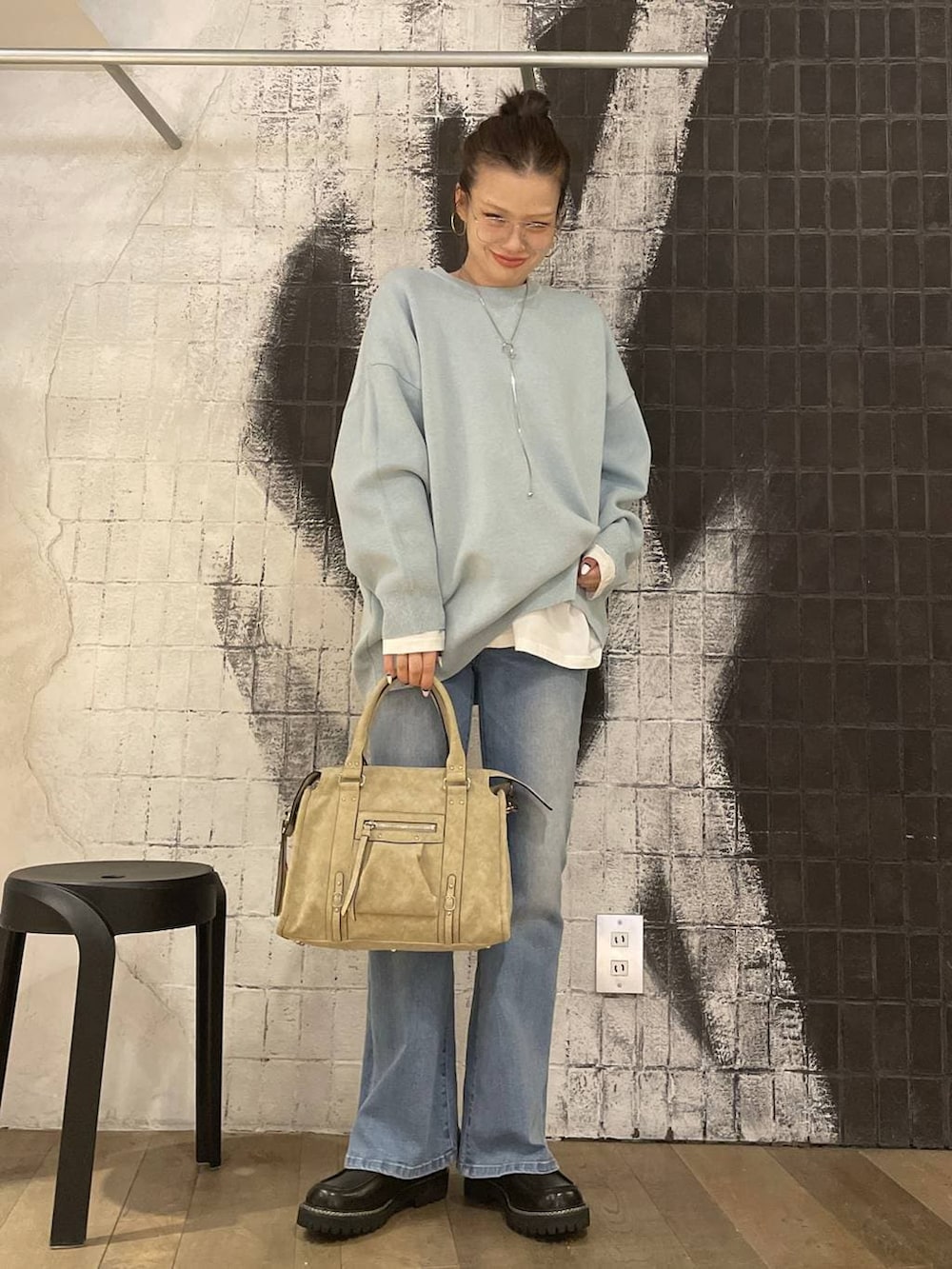 ブルー系のニット/セーター、ベージュ系のボストンバッグ、ホワイト系のTシャツ/カットソーを着用したレディースの冬コーディネートの7枚目の写真