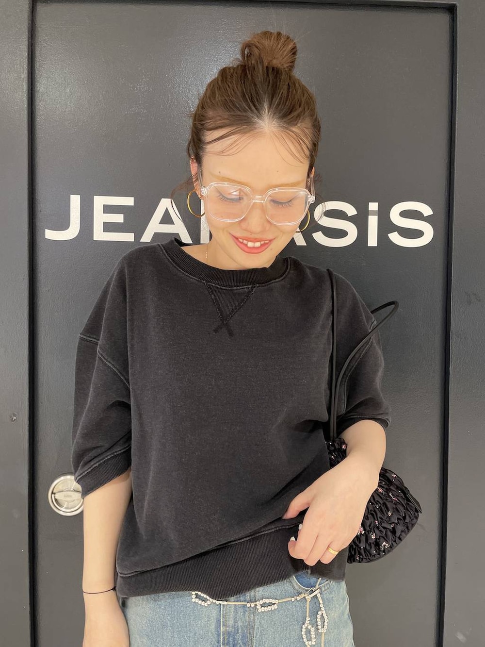 ブルー系のデニムパンツ、ブラック系のスウェット、ブラック系のショルダーバッグを着用したレディースの夏コーディネートの2枚目の写真