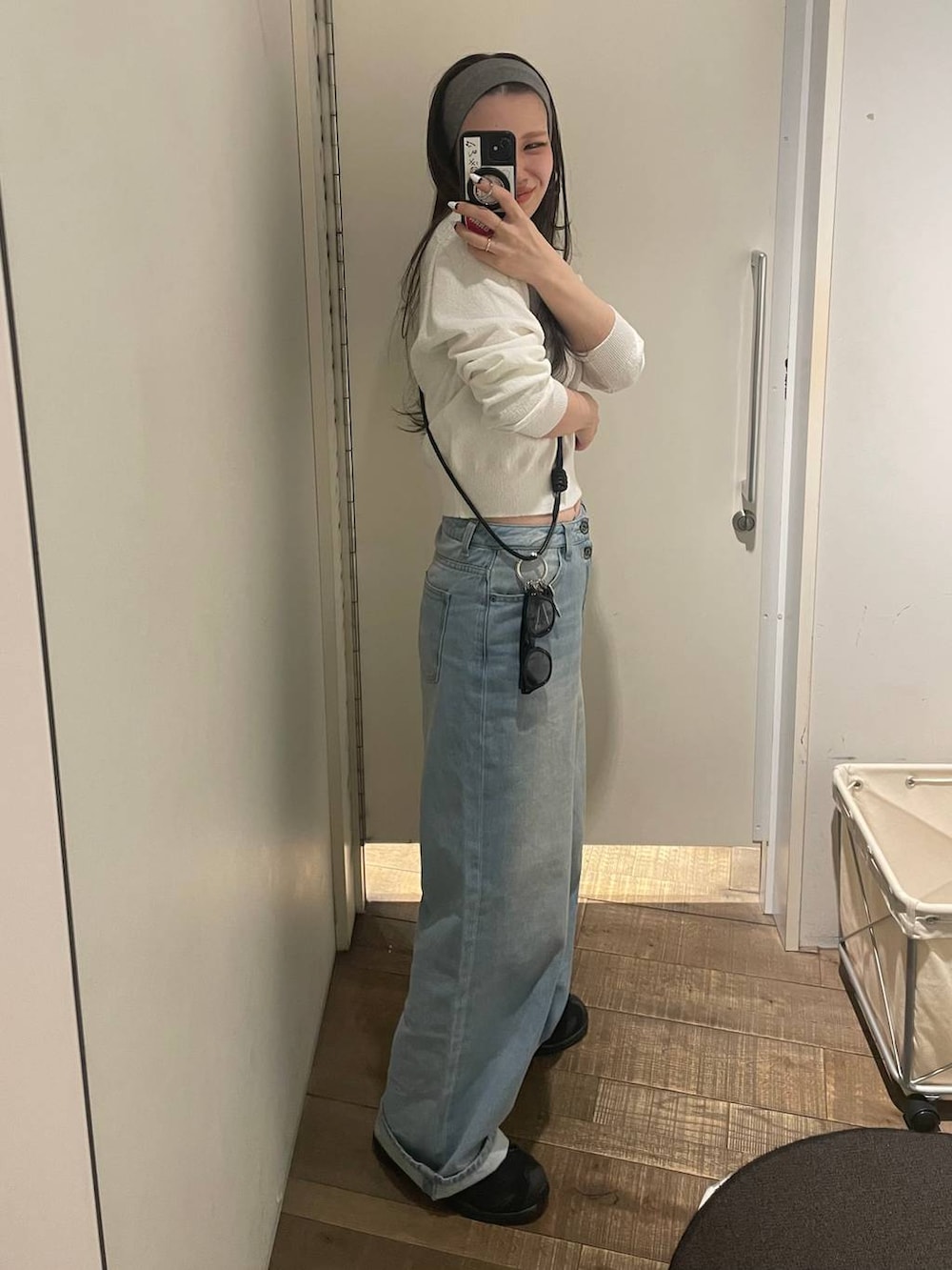 ブルー系のデニムパンツ、ホワイト系のポロシャツ、イエロー系のメガネを着用したレディースの冬コーディネートの2枚目の写真