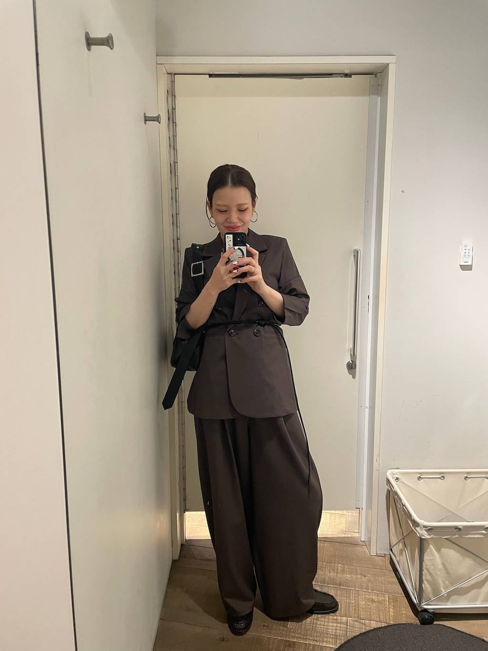 ブラウン系のテーラードジャケット、ブラック系のボストンバッグ、ブラウン系のスラックスを着用したレディースの冬コーディネートの4枚目の写真