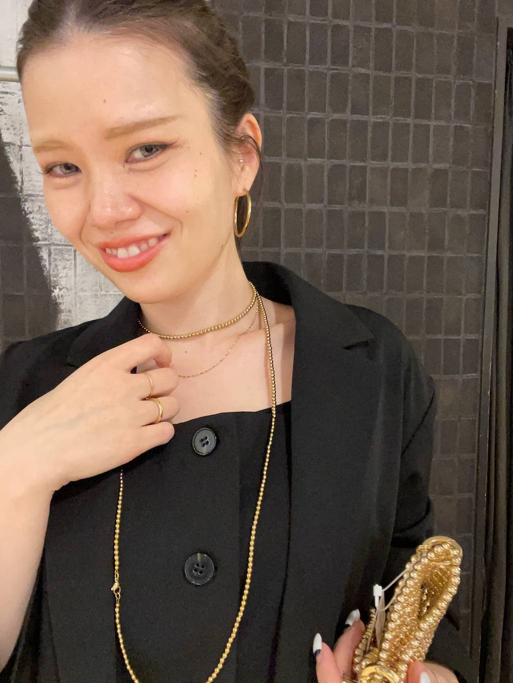 ブラック系のテーラードジャケット、ブラック系のローファー、ゴールド系のピアス（両耳用）を着用したレディースの冬コーディネートの3枚目の写真