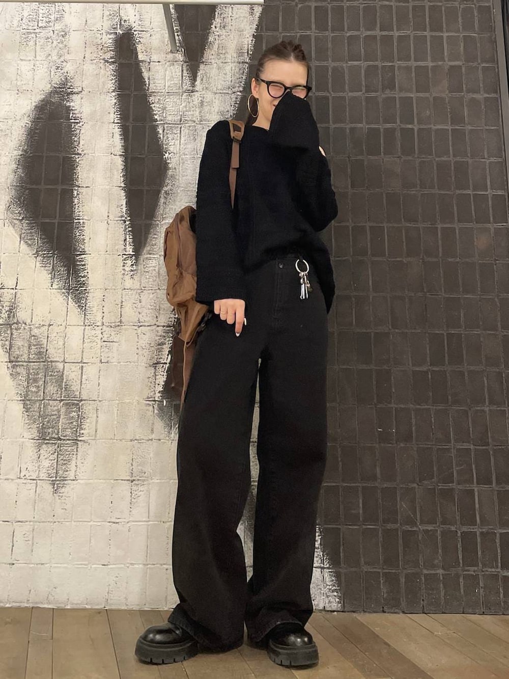 ブラック系のデニムパンツ、ブラック系のニット/セーター、ブラウン系のバックパック/リュックを着用したレディースの冬コーディネートの8枚目の写真