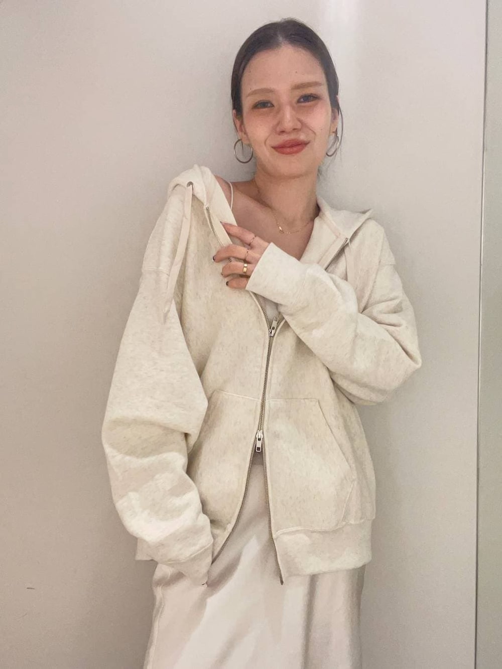 ベージュ系のパーカー、ホワイト系のキャミソール、ホワイト系のスカートを着用したレディースの冬コーディネートの6枚目の写真