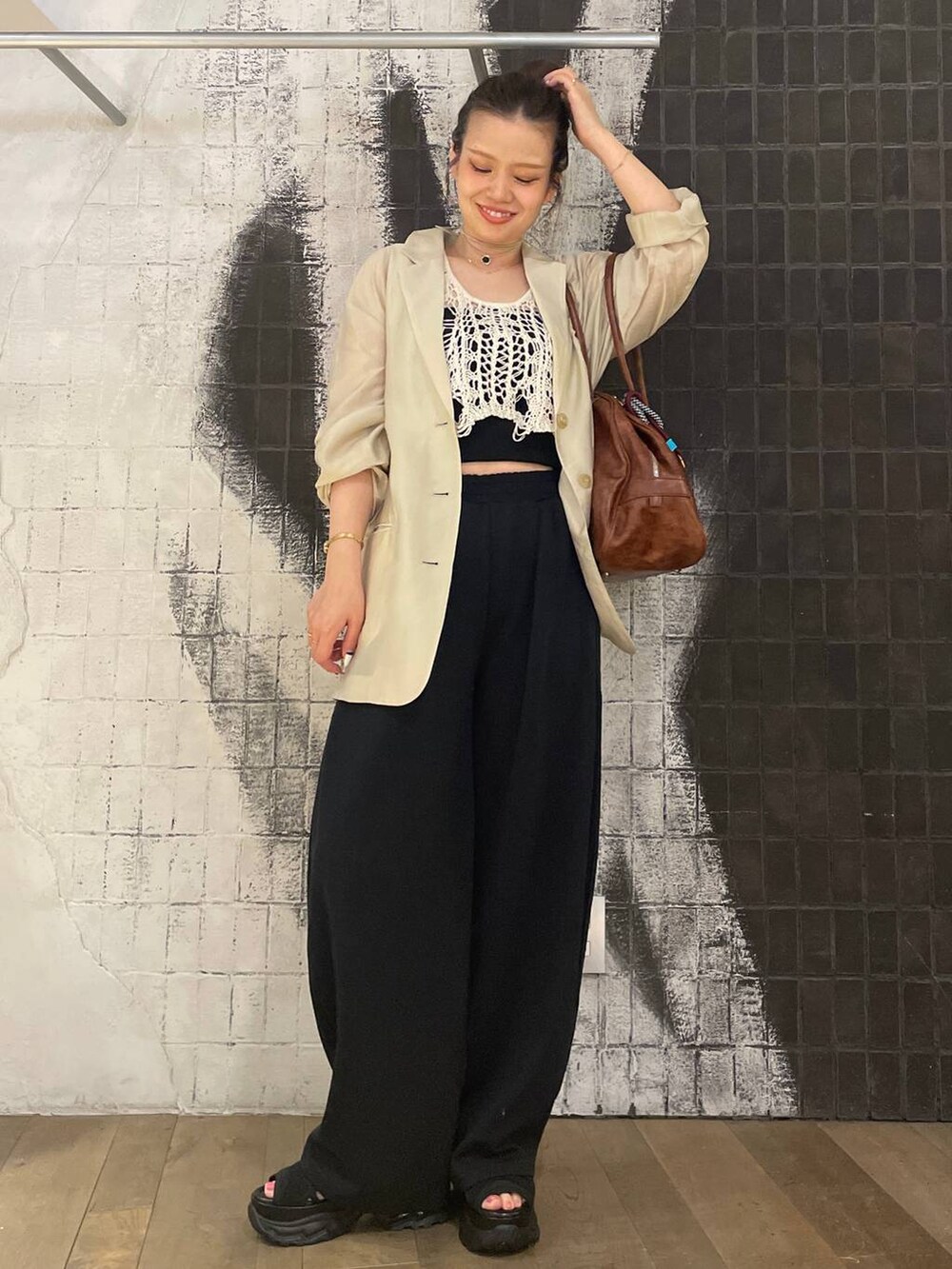 ホワイト系のベスト、ブラック系のサンダル、ブラウン系のボストンバッグを着用したレディースの夏コーディネートの2枚目の写真