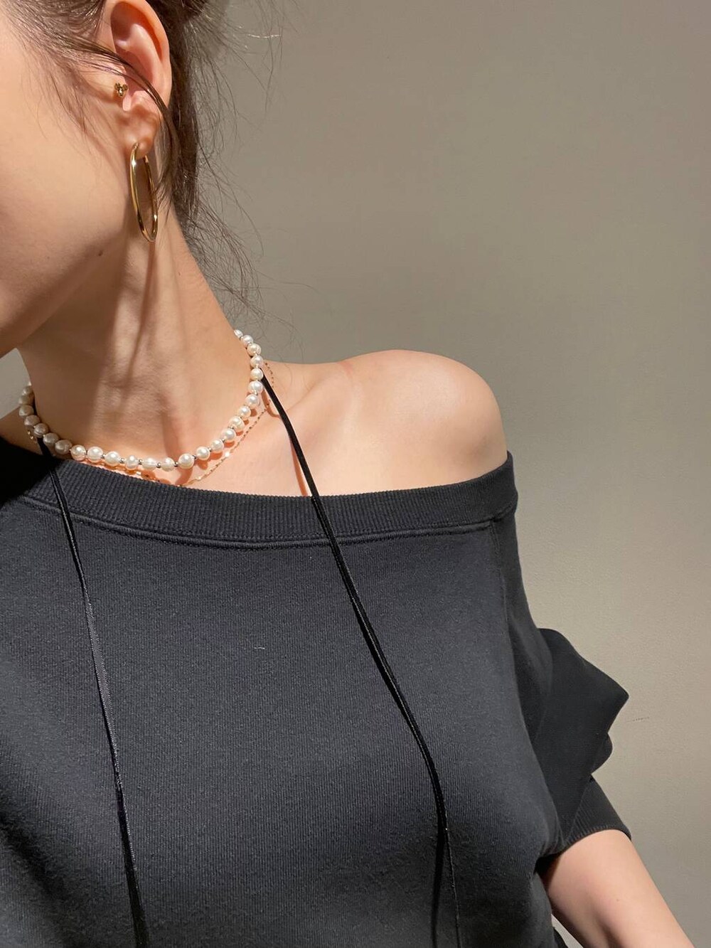 ブルー系のデニムパンツ、ブラック系のスウェット、ゴールド系のピアス（両耳用）を着用したレディースの秋コーディネートの2枚目の写真