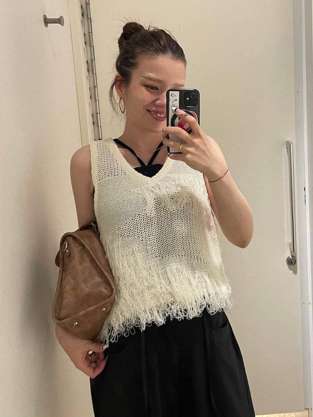 ベージュ系のモカシン/デッキシューズ、ブラウン系のボストンバッグ、ホワイト系のベストを着用したレディースの春コーディネートの4枚目の写真