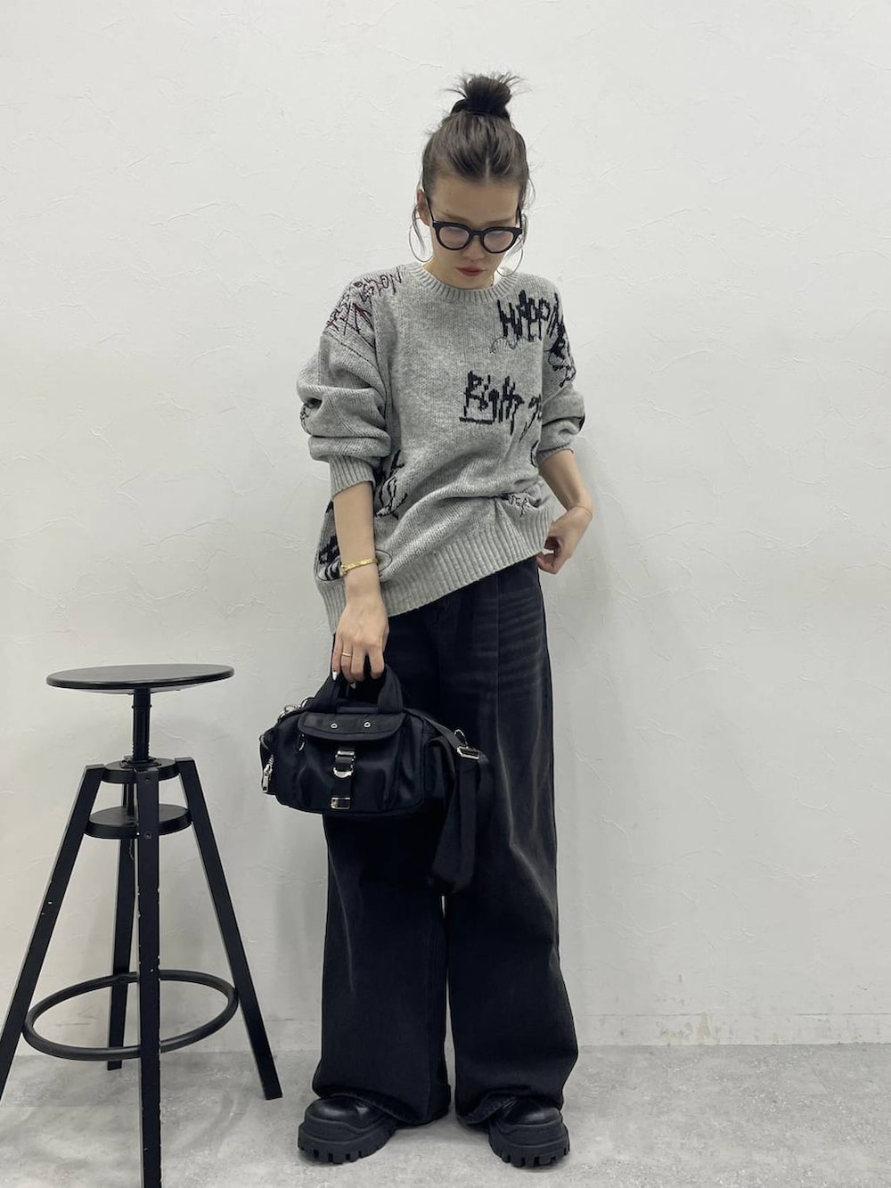 グレー系のデニムパンツ、ブラック系のブーツ、ブラック系のボストンバッグを着用したレディースの冬コーディネートの3枚目の写真