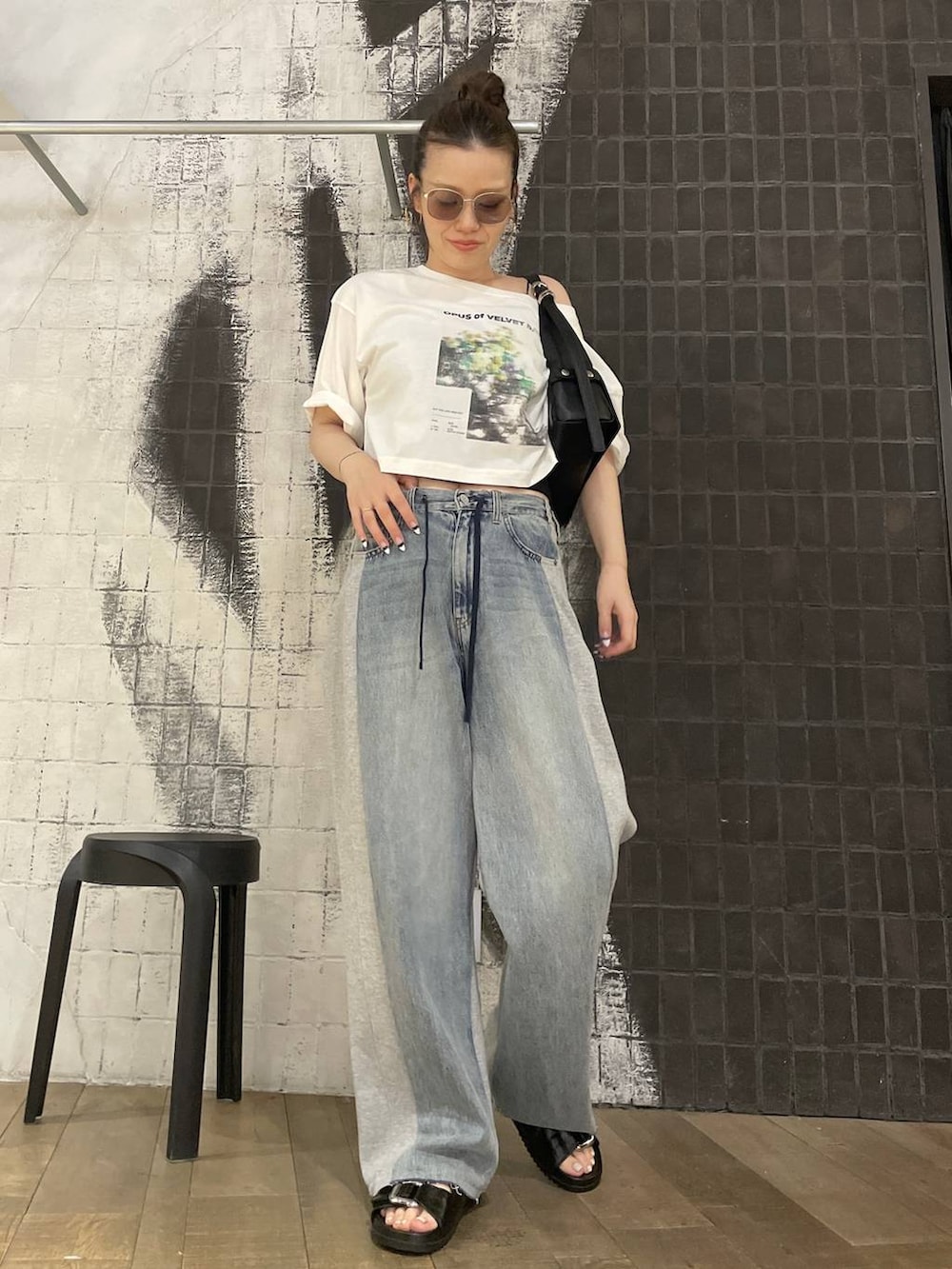 ブルー系のデニムパンツ、ブラック系のショルダーバッグ、ブラック系のサンダルを着用したレディースの夏コーディネートの2枚目の写真