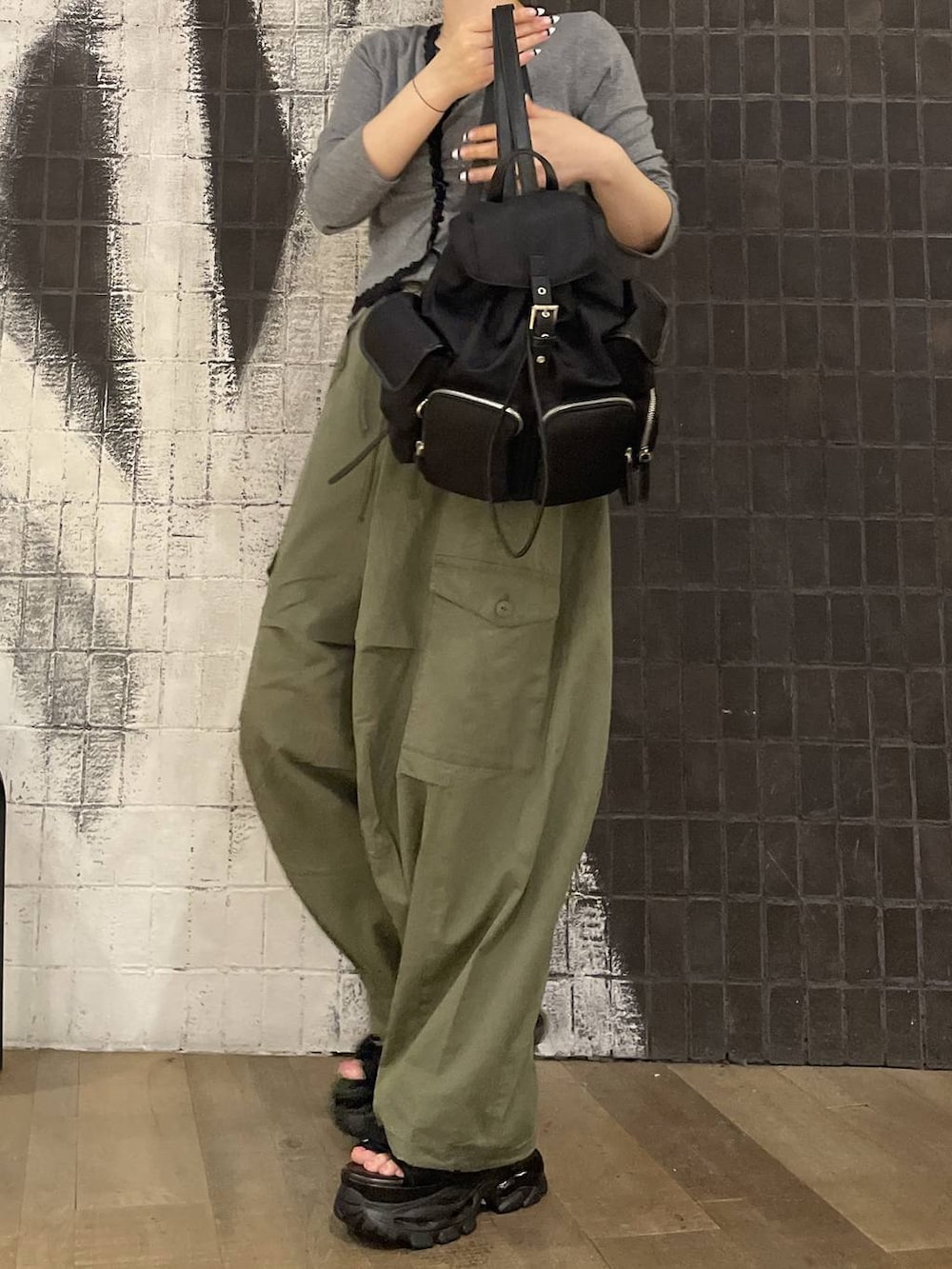 グリーン系のカーゴパンツ、ブラック系のバックパック/リュック、グレー系のカーディガン/ボレロを着用したレディースの夏コーディネートの3枚目の写真
