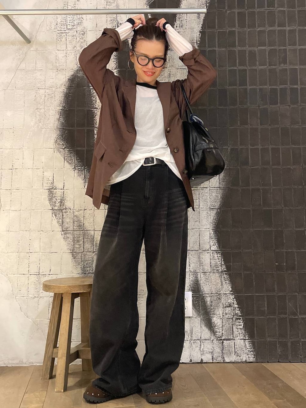 グレー系のデニムパンツ、ブラック系のボストンバッグ、ブラウン系のサンダルを着用したレディースの秋コーディネートの2枚目の写真