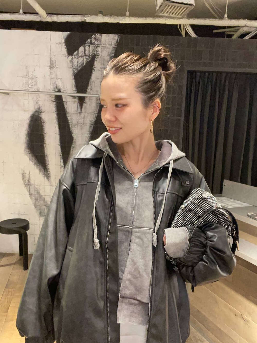 ブラック系のブルゾン、グレー系のパーカー、グレー系のデニムパンツを着用したレディースの冬コーディネートの3枚目の写真