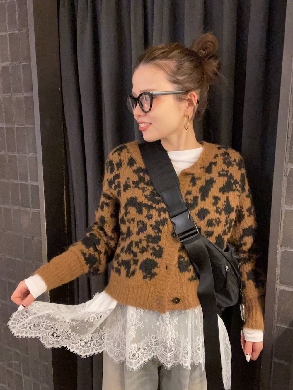 ブラック系のショルダーバッグ、ブルー系のデニムパンツ、ブラック系のブーツを着用したレディースの冬コーディネートの2枚目の写真