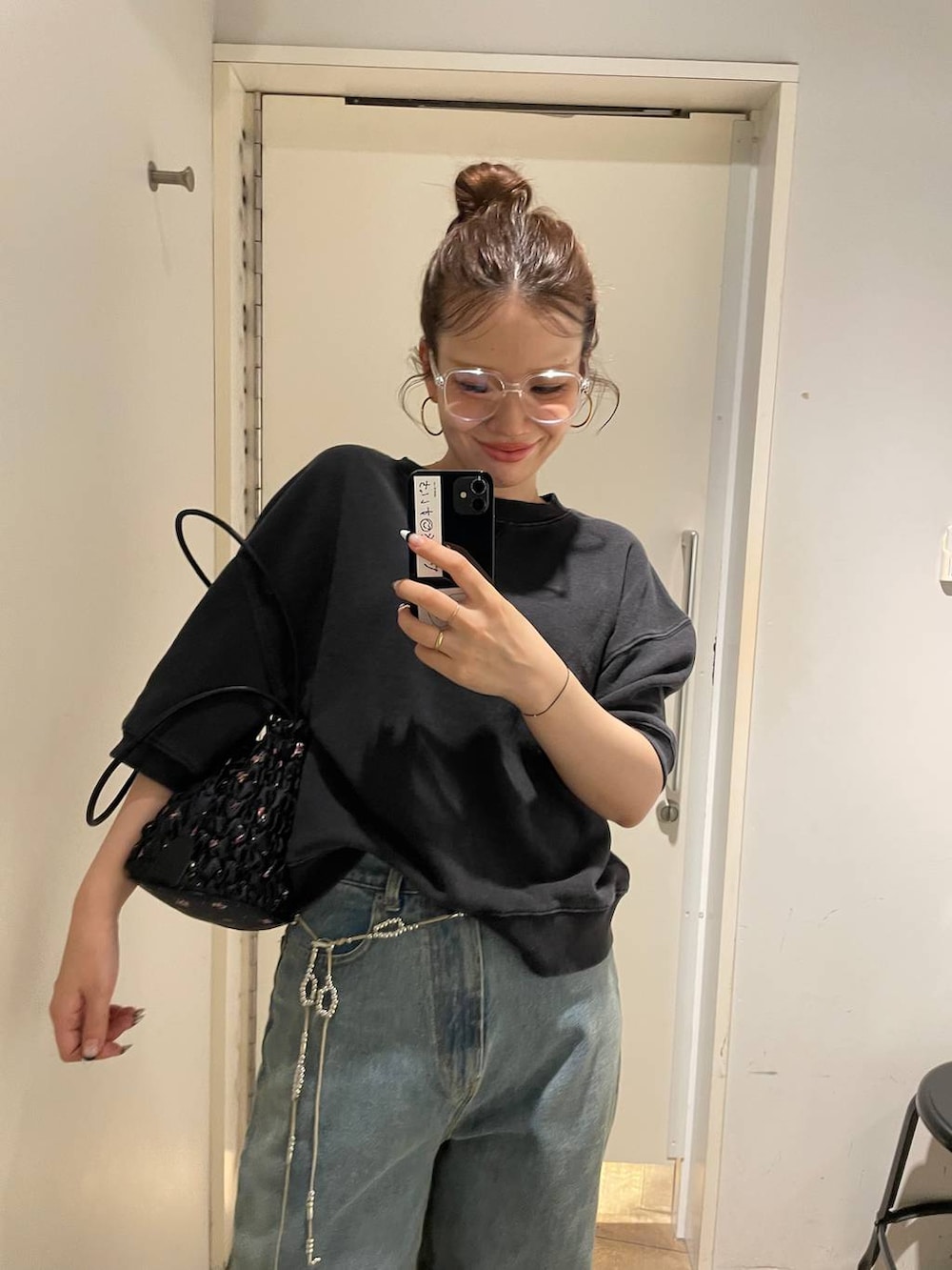 ブルー系のデニムパンツ、ブラック系のスウェット、ブラック系のショルダーバッグを着用したレディースの夏コーディネートの4枚目の写真