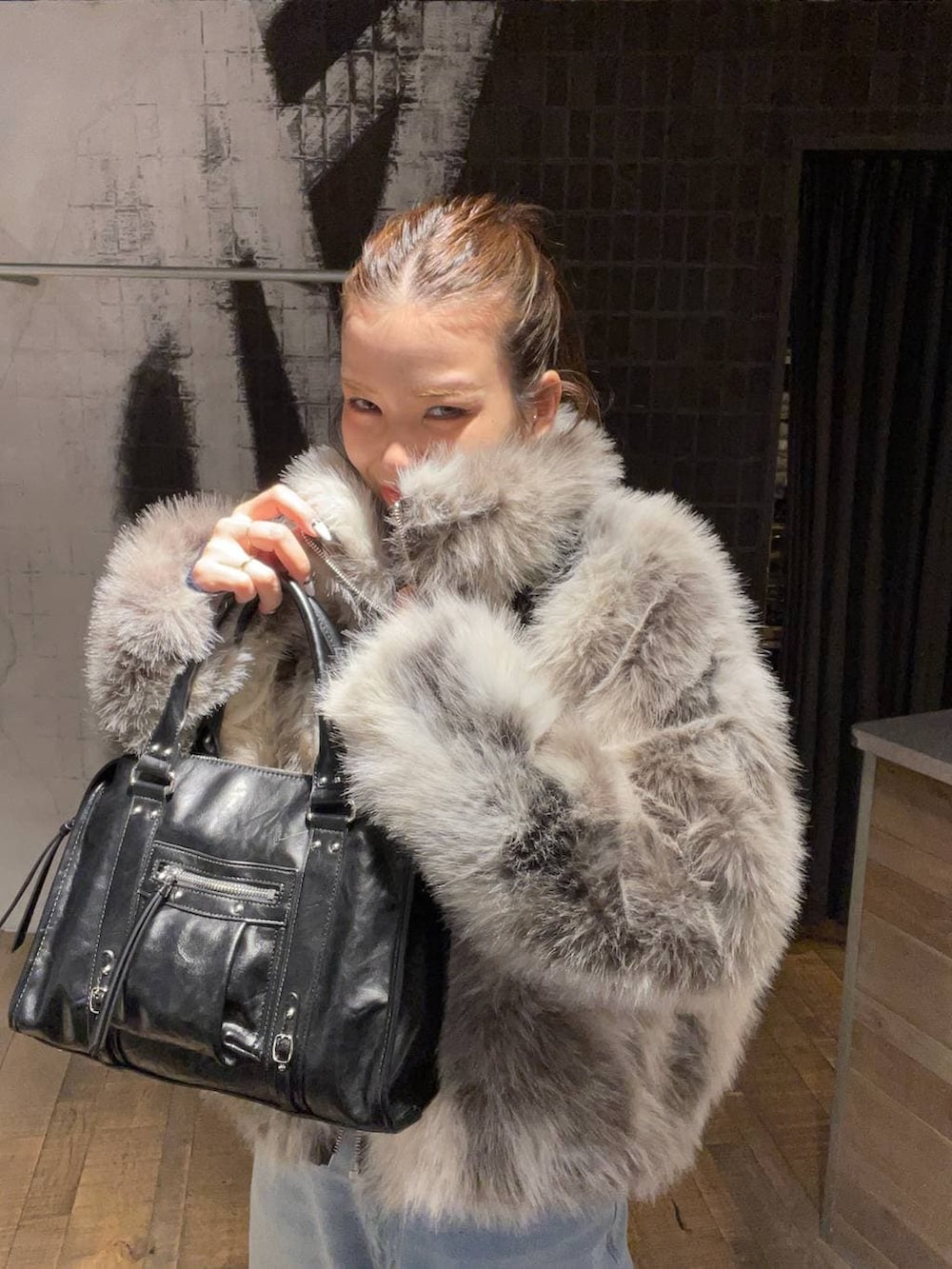 グレー系のブルゾン、ブラック系のボストンバッグ、ブルー系のニット/セーターを着用したレディースの冬コーディネートの4枚目の写真