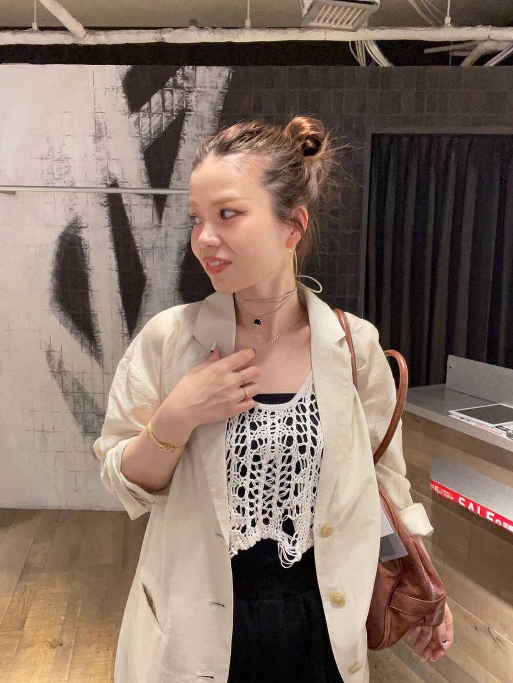 ホワイト系のベスト、ブラック系のサンダル、ブラウン系のボストンバッグを着用したレディースの夏コーディネートの3枚目の写真