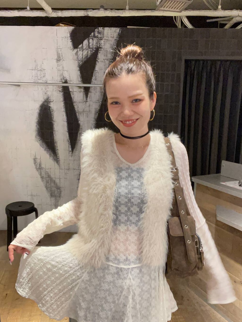 ホワイト系のベスト、ブルー系のデニムパンツ、ブラウン系のショルダーバッグを着用したレディースの秋コーディネートの3枚目の写真