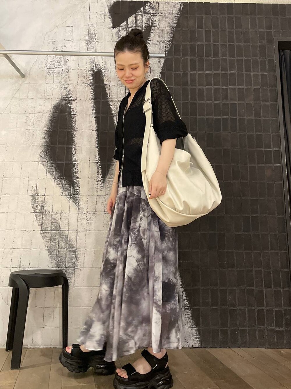 グレー系のスカート、ブラック系のパーカー、ブラック系のサンダルを着用したレディースの春コーディネートの2枚目の写真
