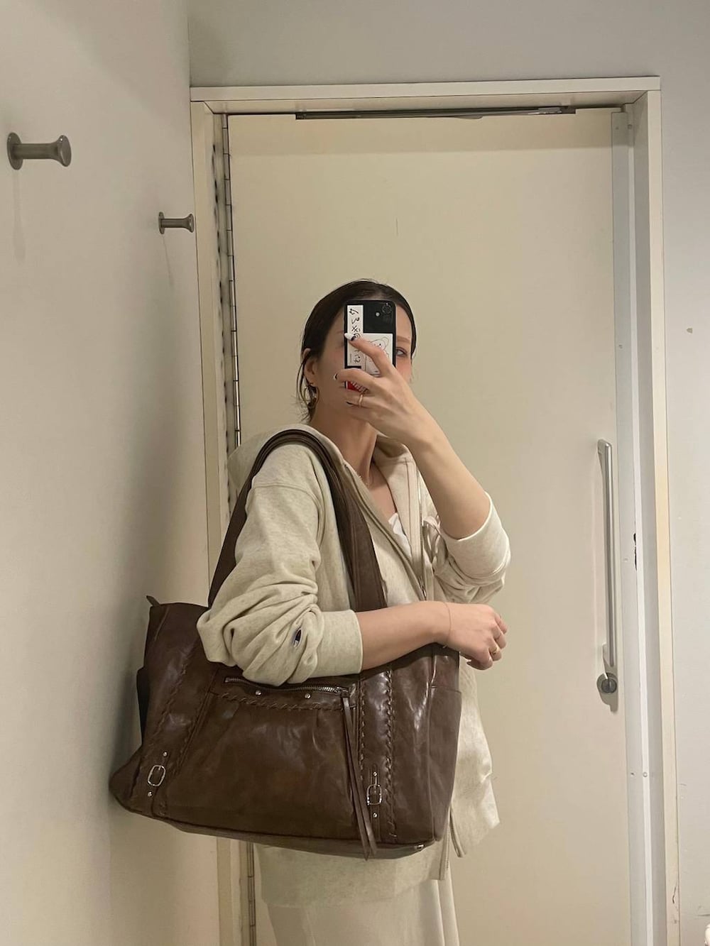 ベージュ系のパーカー、ホワイト系のキャミソール、ホワイト系のスカートを着用したレディースの冬コーディネートの5枚目の写真