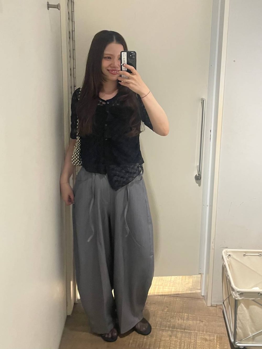 シルバー系のハンドバッグ、グレー系のスラックス、ブラック系のバレエシューズを着用したレディースの夏コーディネートの2枚目の写真