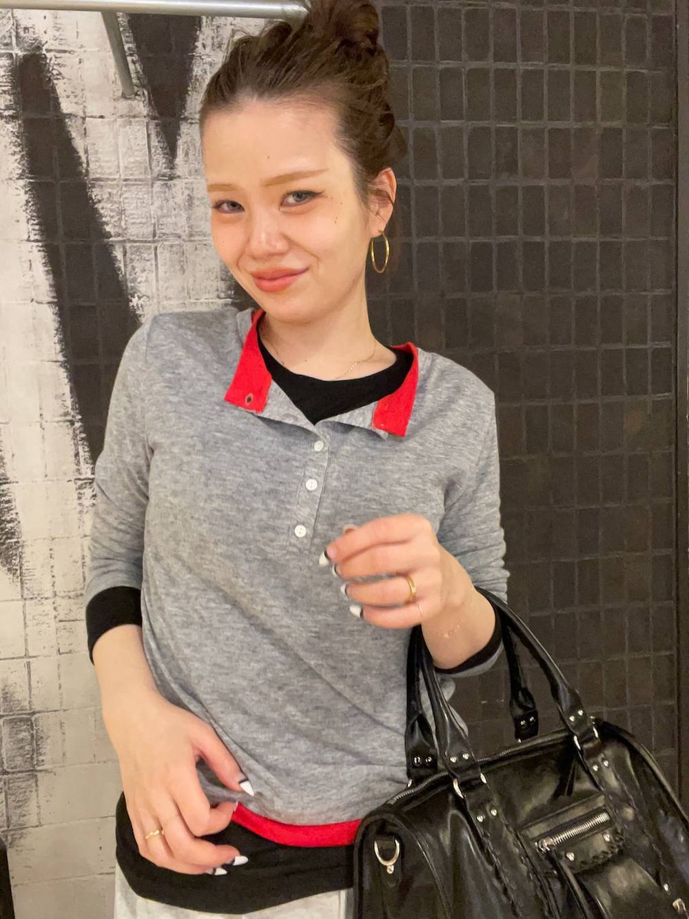 ブラック系のスニーカー、ブラック系のボストンバッグ、グレー系のスカートを着用したレディースの春コーディネートの2枚目の写真