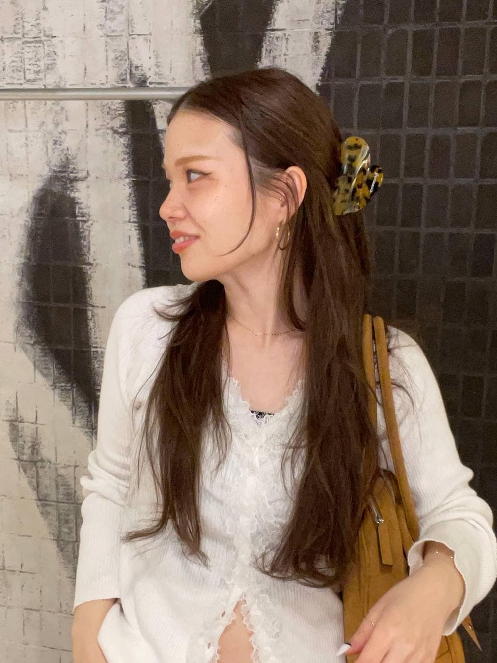 ブラウン系のボストンバッグ、ベージュ系のモカシン/デッキシューズ、ブルー系のデニムパンツを着用したレディースの春コーディネートの5枚目の写真