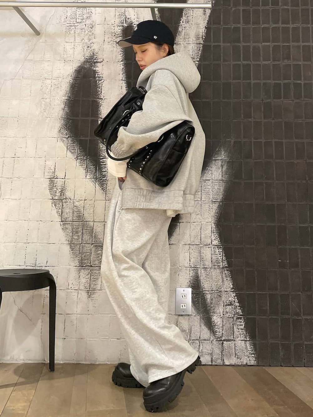 グレー系のパーカー、ブラック系のトートバッグ、ブラック系のブーツを着用したレディースの秋コーディネートの3枚目の写真