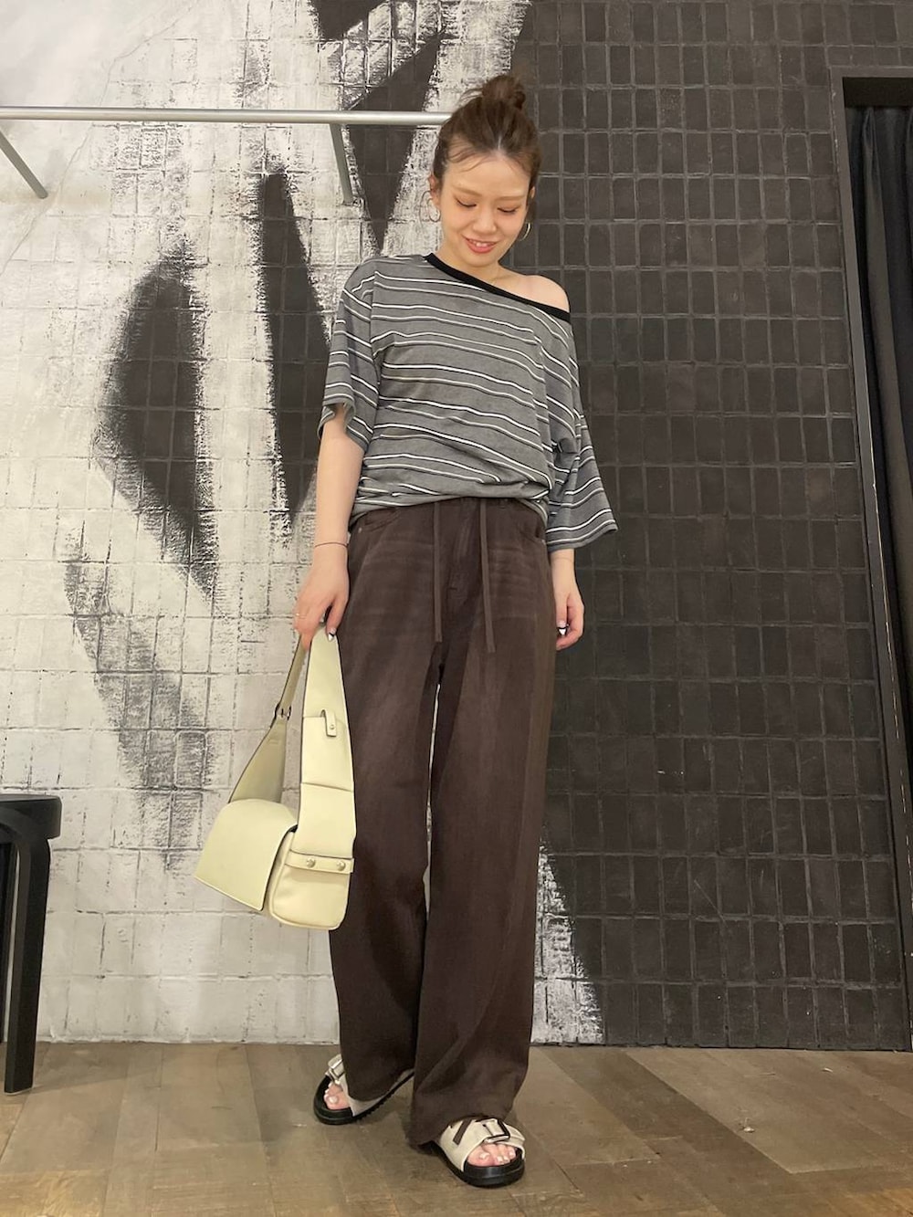 グレー系のTシャツ/カットソー、ブラウン系のデニムパンツ、ホワイト系のサンダルを着用したレディースの夏コーディネートの2枚目の写真