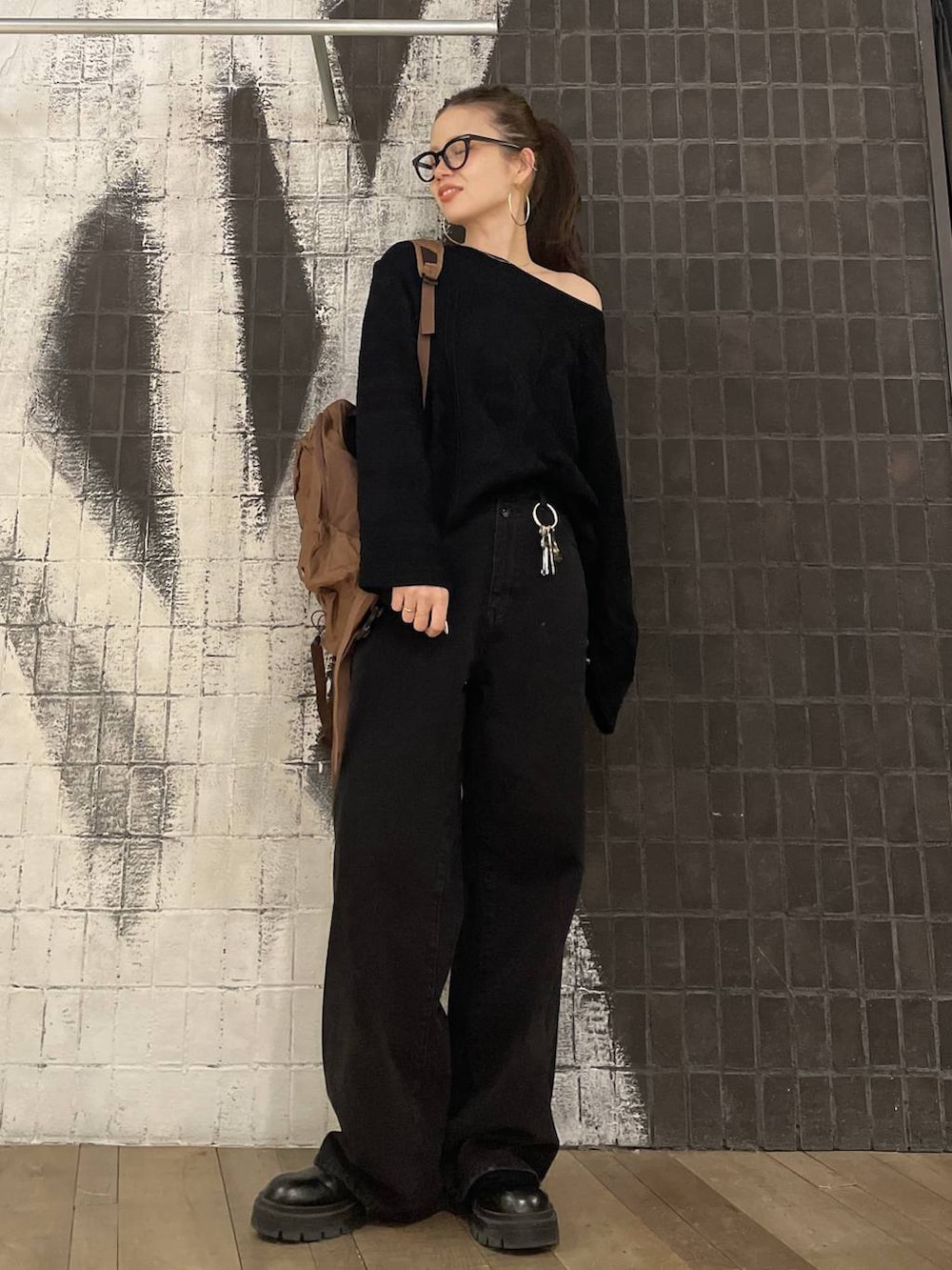 ブラック系のデニムパンツ、ブラック系のニット/セーター、ブラウン系のバックパック/リュックを着用したレディースの冬コーディネートの2枚目の写真