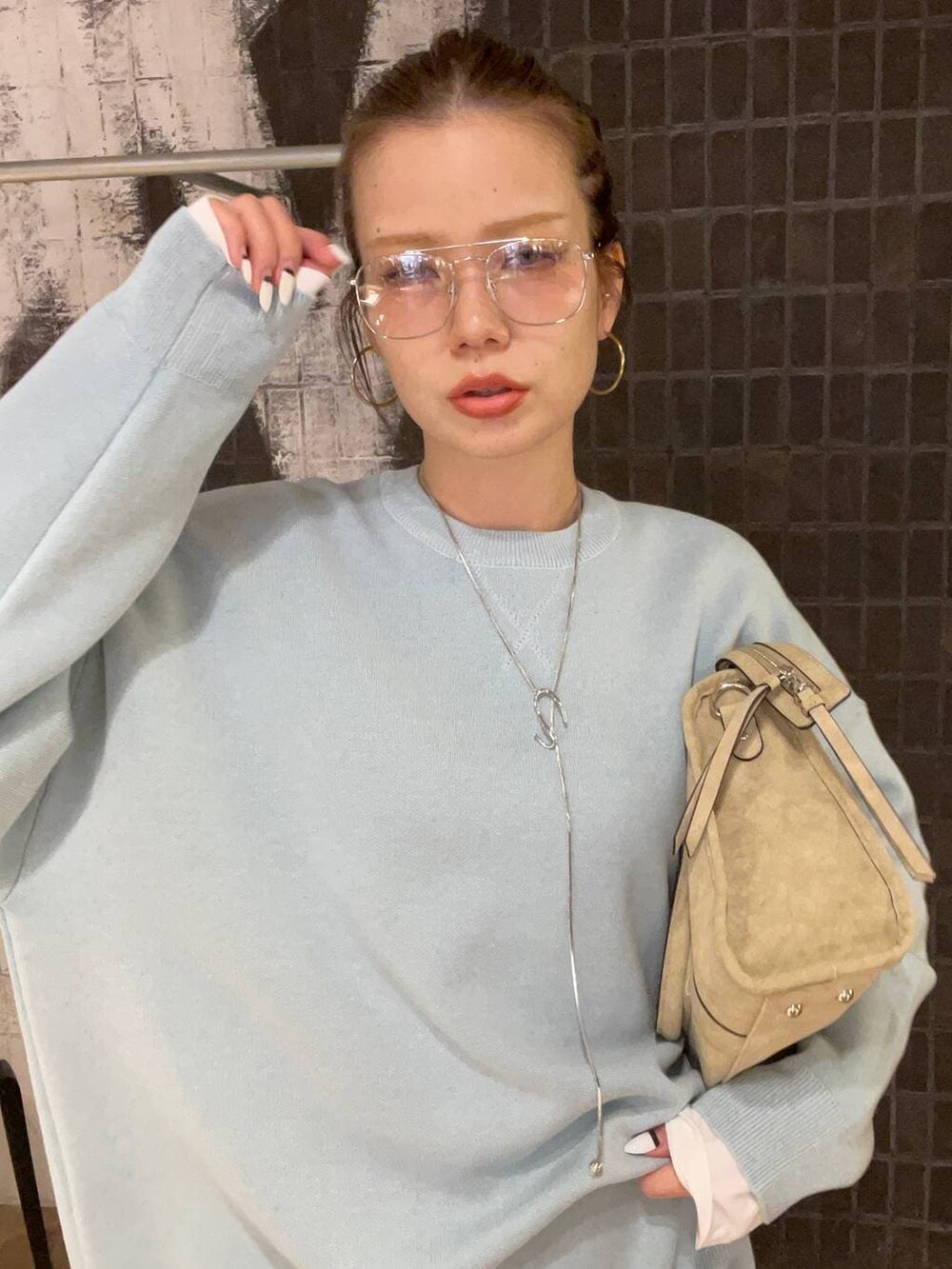 ブルー系のニット/セーター、ベージュ系のボストンバッグ、ホワイト系のTシャツ/カットソーを着用したレディースの冬コーディネートの2枚目の写真