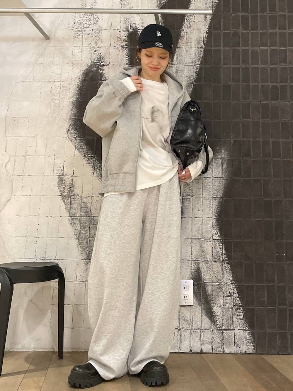 グレー系のパーカー、ブラック系のトートバッグ、ブラック系のブーツを着用したレディースの秋コーディネートの2枚目の写真