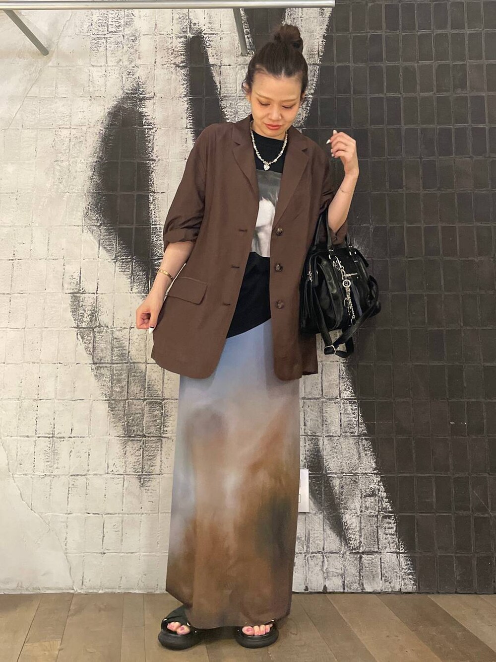 ブラック系のボストンバッグ、ブラック系のサンダル、ブラウン系のテーラードジャケットを着用したレディースの夏コーディネートの4枚目の写真