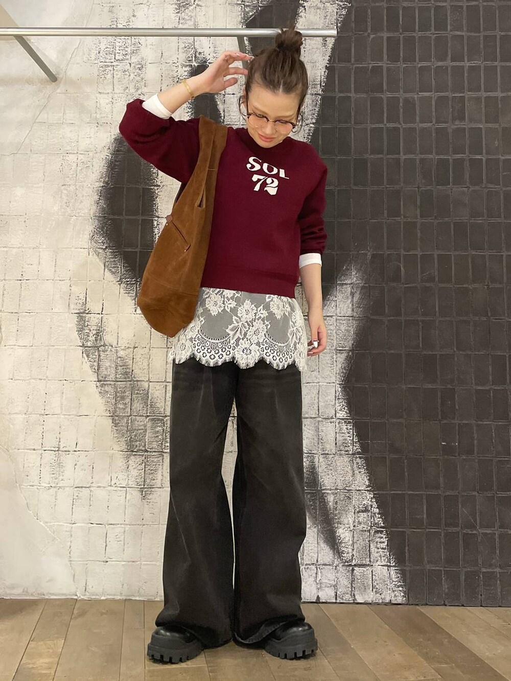 グレー系のデニムパンツ、ブラック系のブーツ、ブラウン系のトートバッグを着用したレディースの秋コーディネートの7枚目の写真