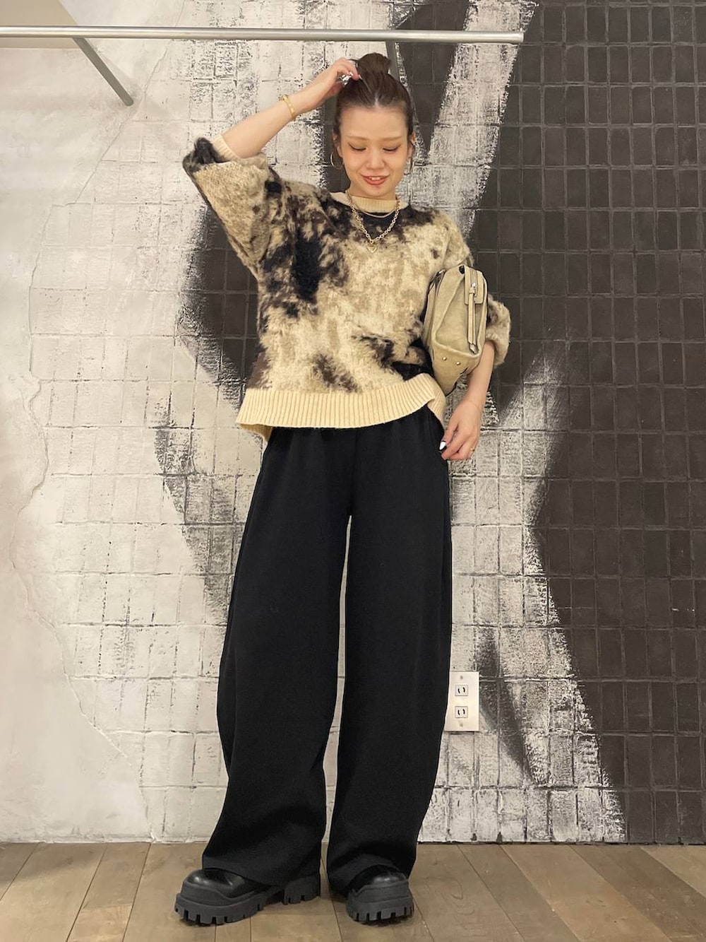 ブラウン系のニット/セーター、ベージュ系のボストンバッグ、ブラック系のブーツを着用したレディースの秋コーディネートの2枚目の写真