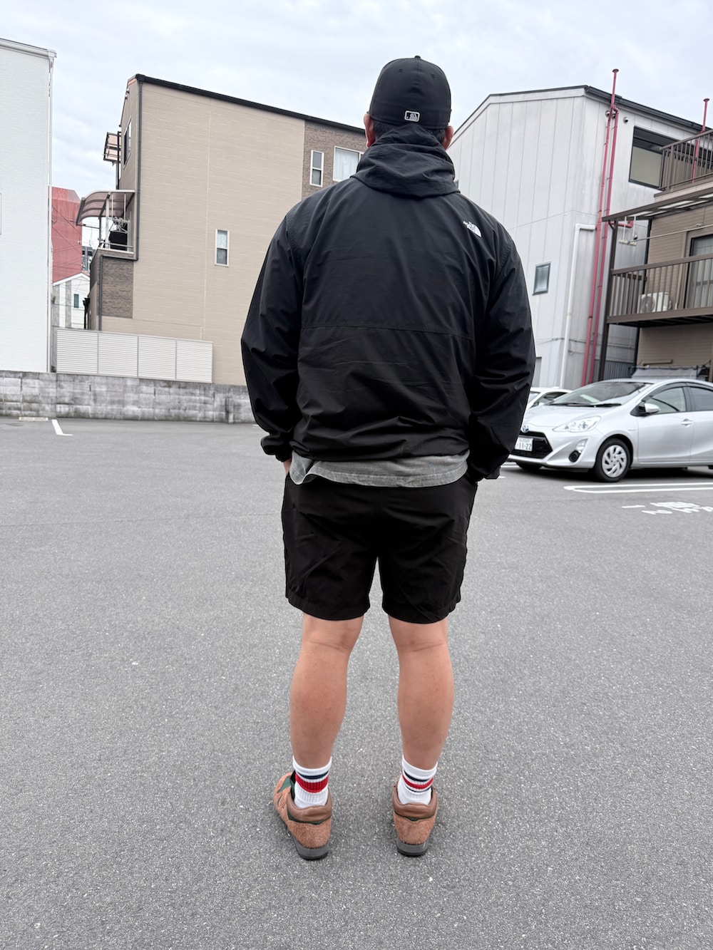 ブラウン系のスニーカー、ベージュ系のパンツ、ブラック系のマウンテンパーカーを着用したメンズの春コーディネートの2枚目の写真