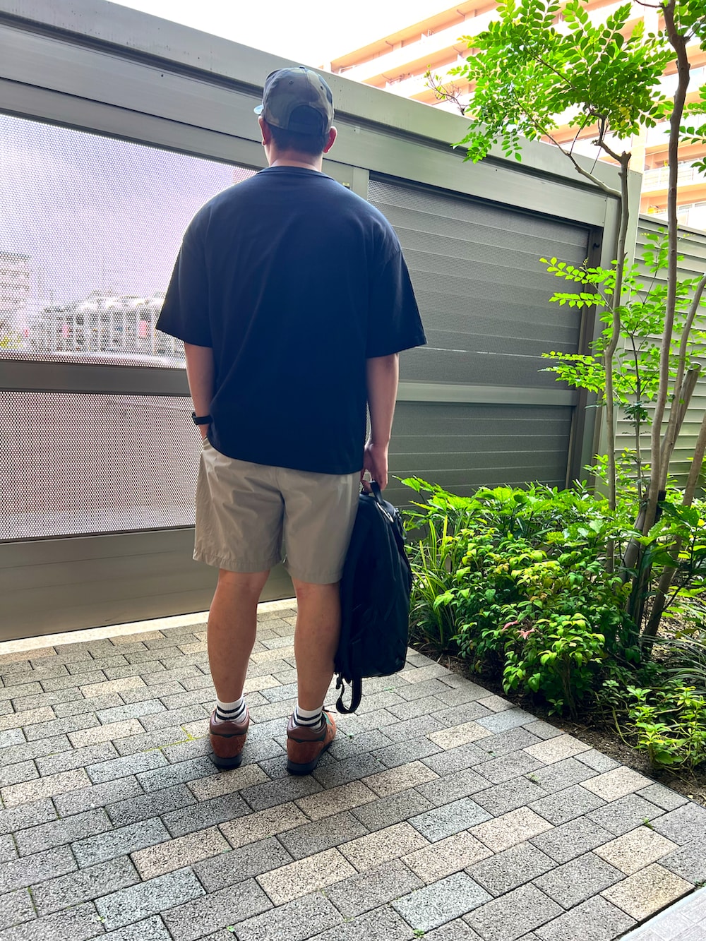 ブラウン系のスニーカー、ブラック系のバックパック/リュック、ベージュ系のパンツを着用したメンズの夏コーディネートの2枚目の写真