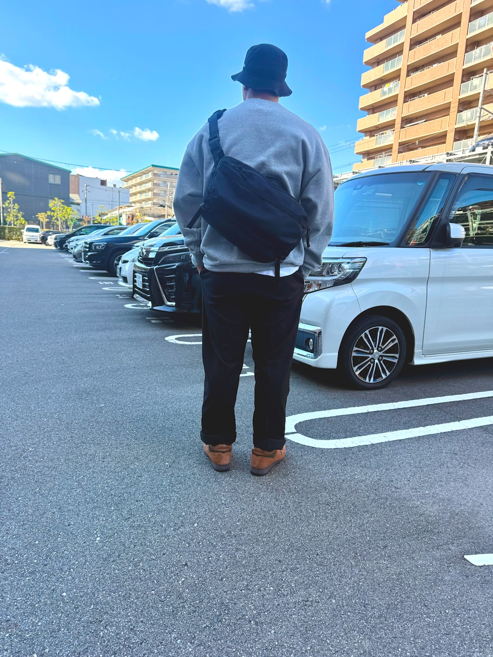 ブラウン系のスニーカー、ブラック系のチノパンツ、グレー系のスウェットを着用したメンズの秋コーディネートの2枚目の写真