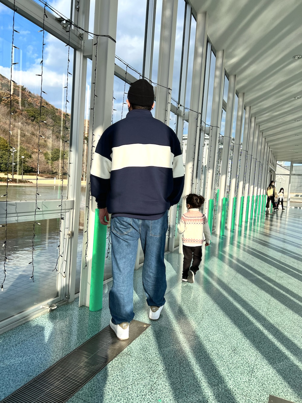 ホワイト系のスニーカー、ブルー系のデニムパンツ、ブルー系のスウェットを着用したメンズの冬コーディネートの4枚目の写真