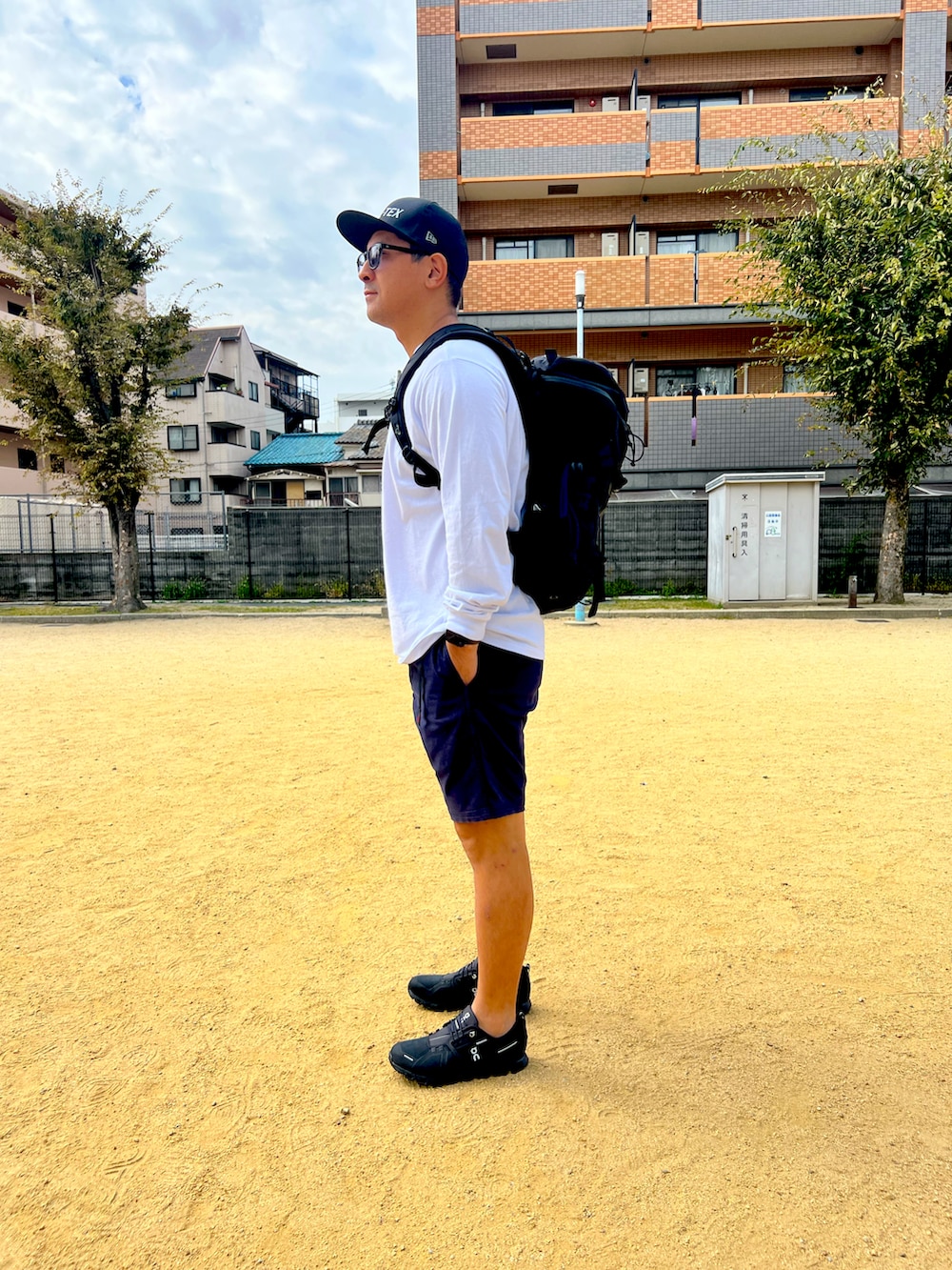 ブラック系のスニーカー、ブルー系のチノパンツ、ホワイト系のTシャツ/カットソーを着用したメンズの秋コーディネートの2枚目の写真