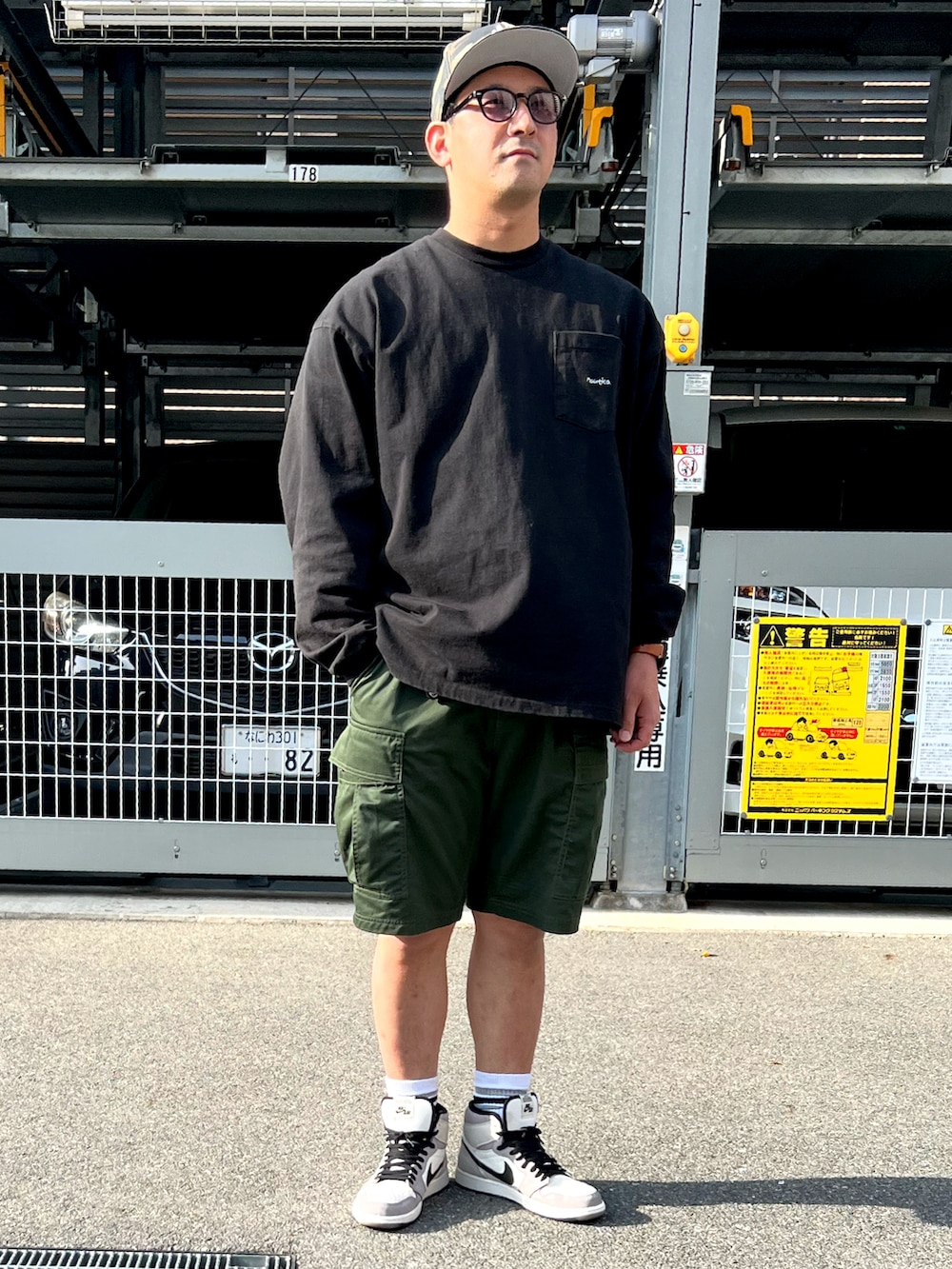 ブラック系のTシャツ/カットソー、グリーン系のカーゴパンツ、グレー系のスニーカーを着用したメンズの春コーディネートの2枚目の写真