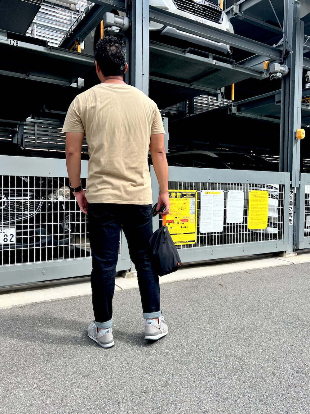 グレー系のスニーカー、ベージュ系のTシャツ/カットソー、ブラック系のデニムパンツを着用したメンズの秋コーディネートの2枚目の写真