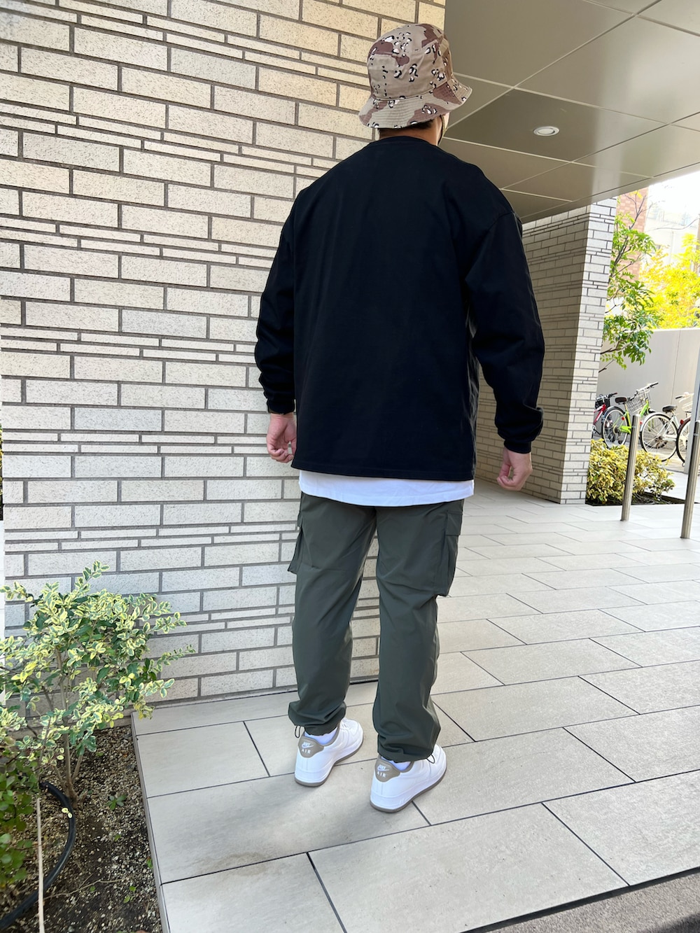 ホワイト系のスニーカー、グリーン系のカーゴパンツ、ブラック系のTシャツ/カットソーを着用したメンズの秋コーディネートの2枚目の写真