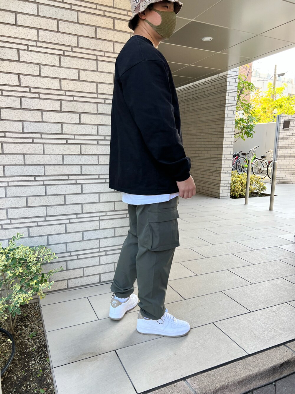 ホワイト系のスニーカー、グリーン系のカーゴパンツ、ブラック系のTシャツ/カットソーを着用したメンズの秋コーディネートの3枚目の写真