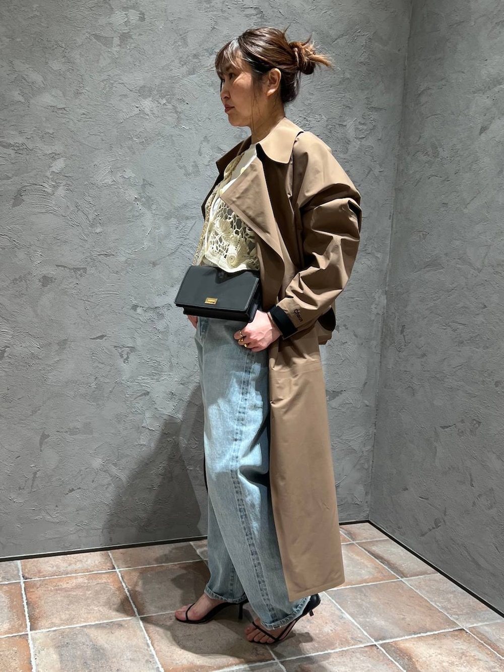 ホワイト系のTシャツ/カットソー、ブルー系のデニムパンツ、ベージュ系のトレンチコートを着用したレディースの冬コーディネートの2枚目の写真