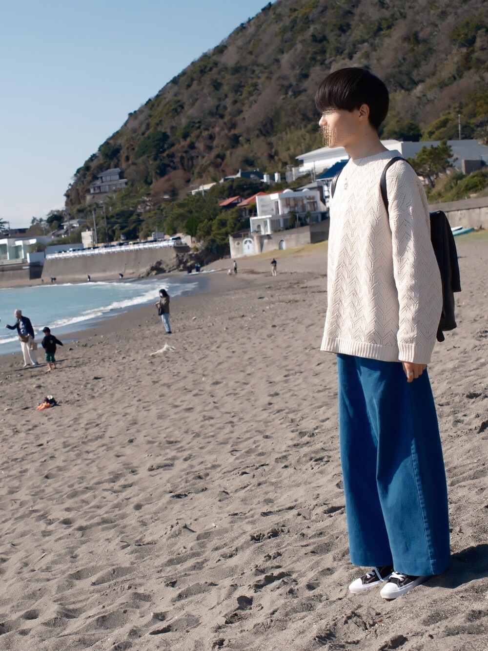 ホワイト系のニット/セーター、ブルー系のデニムパンツ、ブラック系のスニーカーを着用したメンズの春コーディネートの2枚目の写真