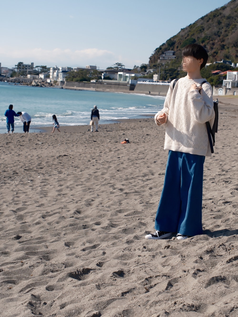 ホワイト系のニット/セーター、ブルー系のデニムパンツ、ブラック系のスニーカーを着用したメンズの春コーディネートの3枚目の写真